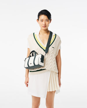 Woman wearing a cable knit sweater and skirt with a handbag on a white background