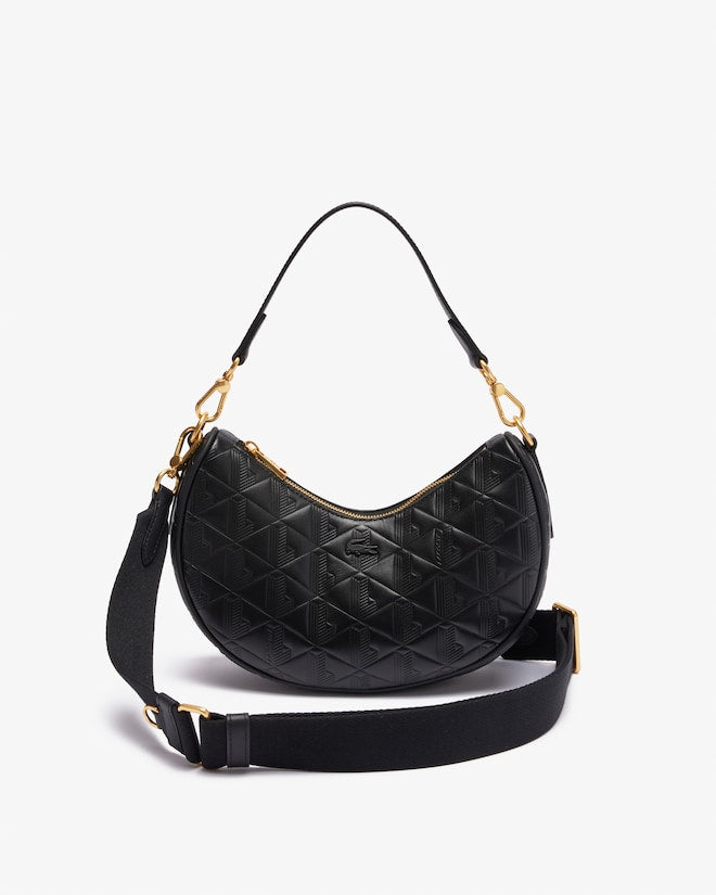 Black quilted handbag with gold accents on a light gray background