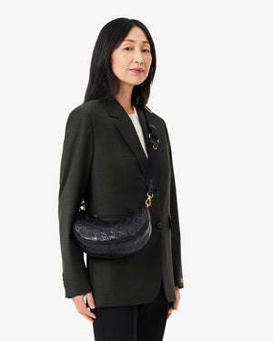 Woman wearing a black blazer with a black bag on a white background