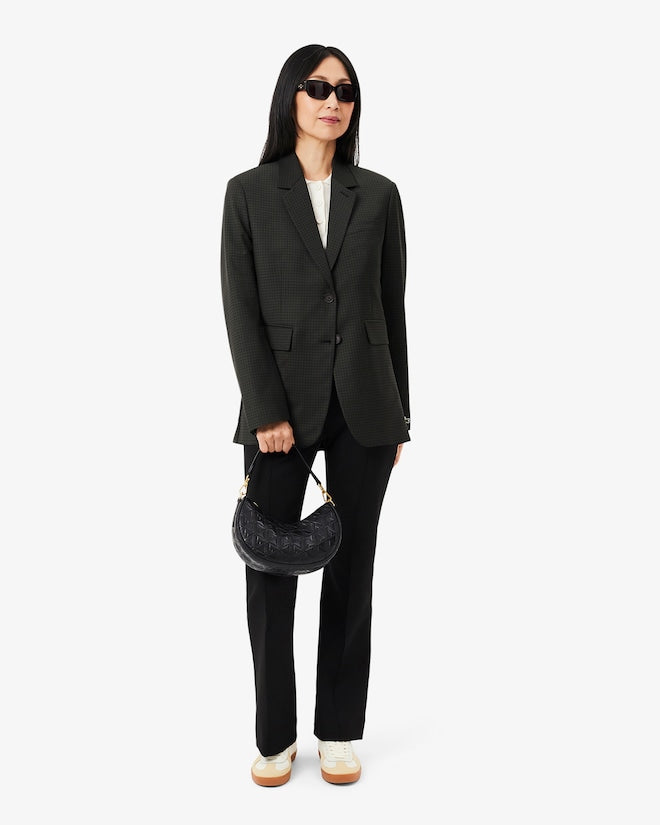 Woman wearing a black suit holding a handbag on a white background